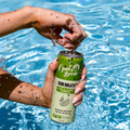 Person holding refreshing can of Owls Brew Rum Mojito by pool